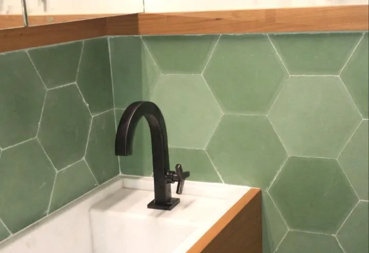 Lavabo reformado com revestimento hexagonal, cuba esculpida e marcenaria em madeira